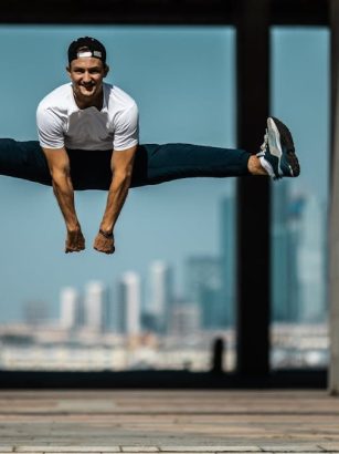 Man performing a split jump on concrete, showcasing fitness and agility.