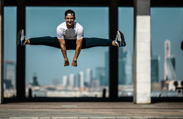 Man performing a split jump on concrete, showcasing fitness and agility.